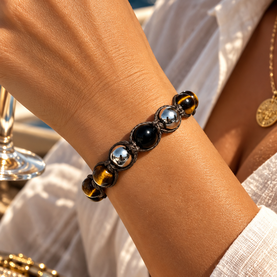 NEXO TIGERAUGE Armband am Handgelenk mit goldbraunen Tigerauge-Perlen, schwarzem Turmalin zwischen zwei Silberperlen und braunem Makramee.
